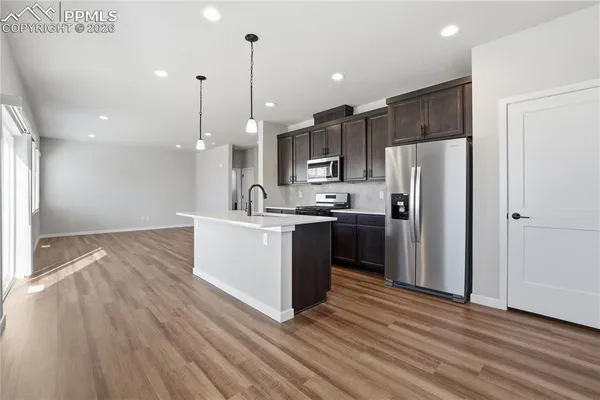 a kitchen with kitchen island a refrigerator a sink and wooden floor