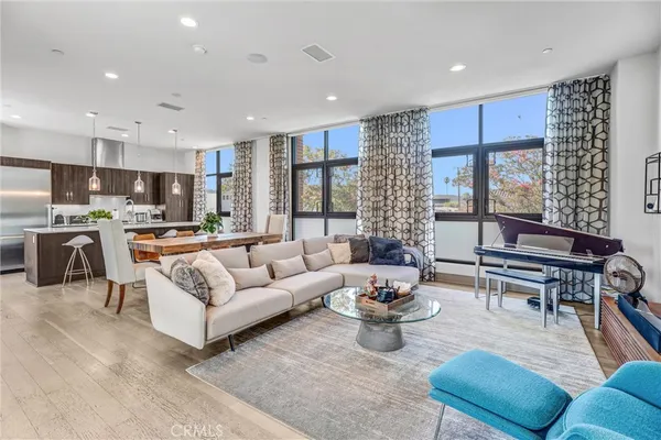 a living room with furniture kitchen view and a large window