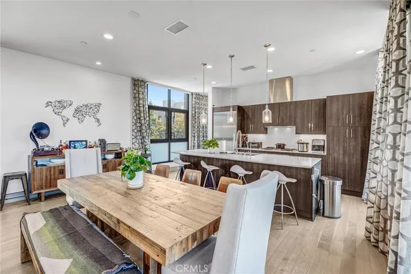 a kitchen with stainless steel appliances a dining table chairs refrigerator and microwave