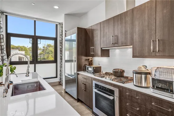 a room with stainless steel appliances kitchen island granite countertop a table chairs and a refrigerator