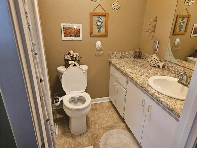a bathroom with a granite countertop toilet a sink and a mirror