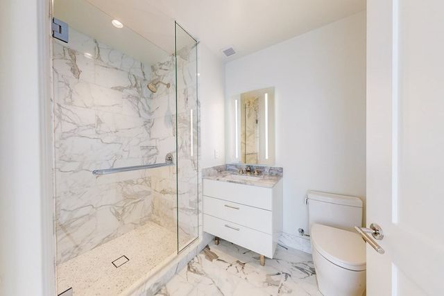 a bathroom with a granite countertop sink a toilet and shower