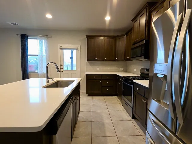 a kitchen with stainless steel appliances granite countertop a sink counter space cabinets and a large window
