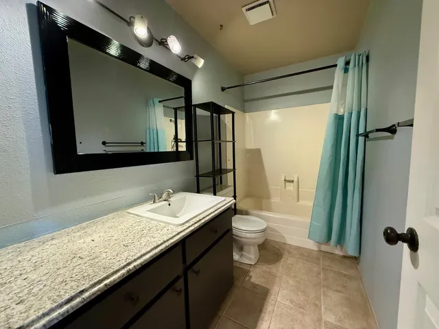a bathroom with a granite countertop sink toilet and shower