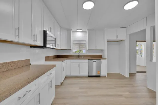 a kitchen with granite countertop white cabinets and stainless steel appliances