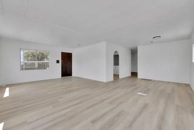 a view of empty room with wooden floor and window