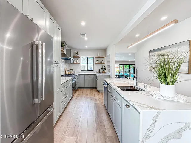 a kitchen with stainless steel appliances a sink a stove a refrigerator cabinets and a counter top space