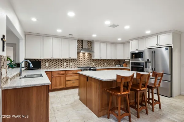 a kitchen with stainless steel appliances granite countertop a table chairs sink refrigerator and microwave