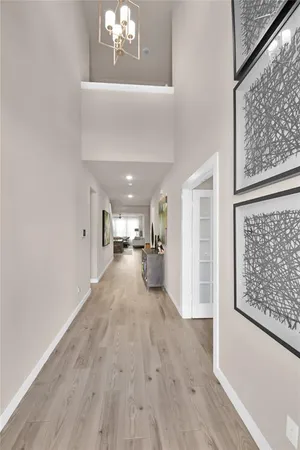 a view of a hallway with wooden floor and a chandelier