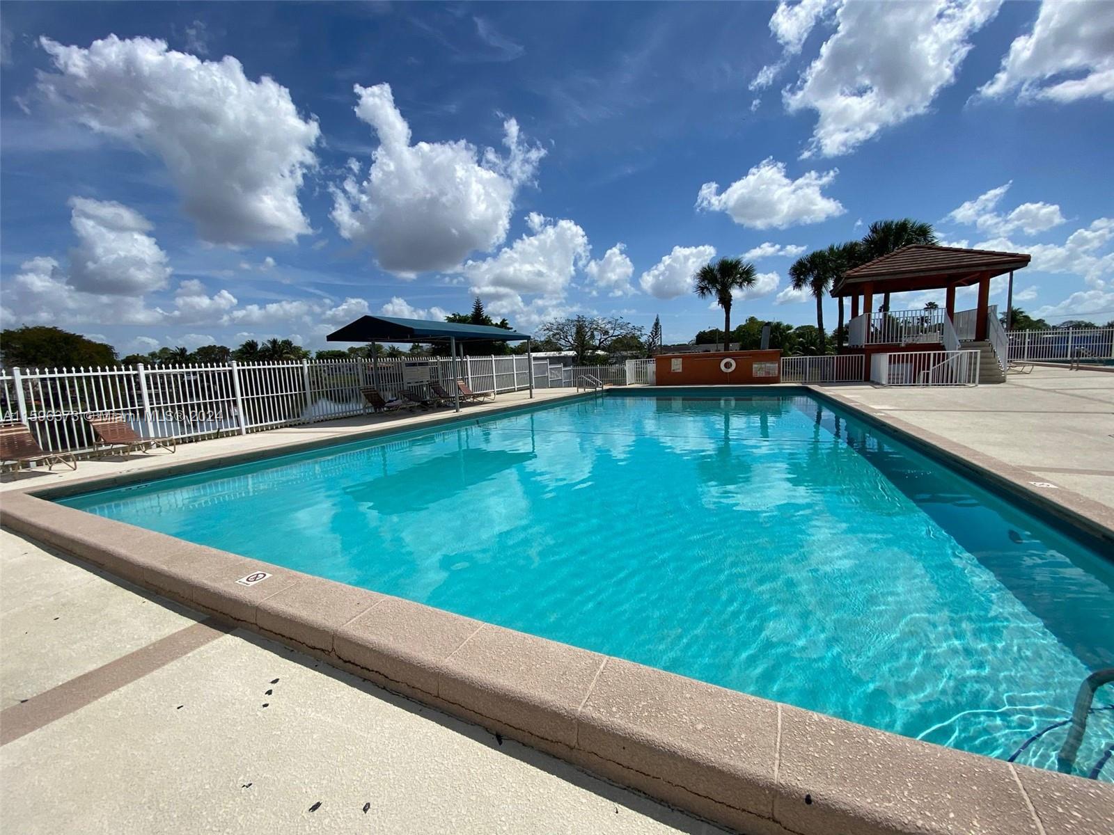 1432 Southwest 129th Court, Unit 2 Miami, FL 33184 - Photo 9 of 12 a view of a swimming pool with a table and chairs under an umbrella
