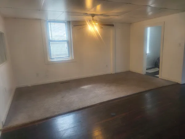 an empty room with wooden floor and windows with curtains