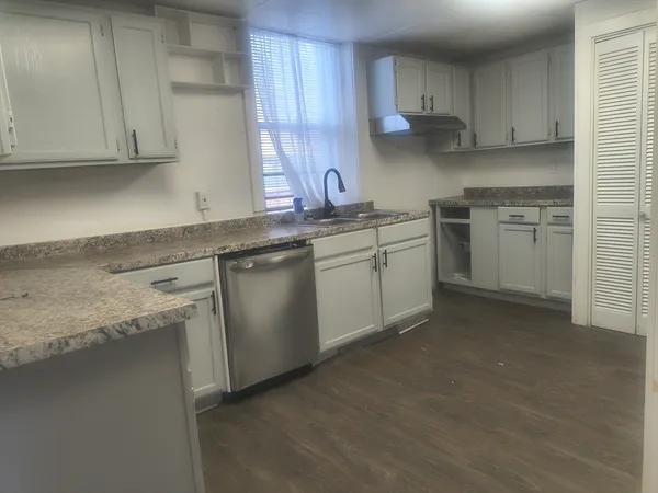 a kitchen with white cabinets sink and stove