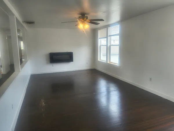 an empty room with wooden floor and windows