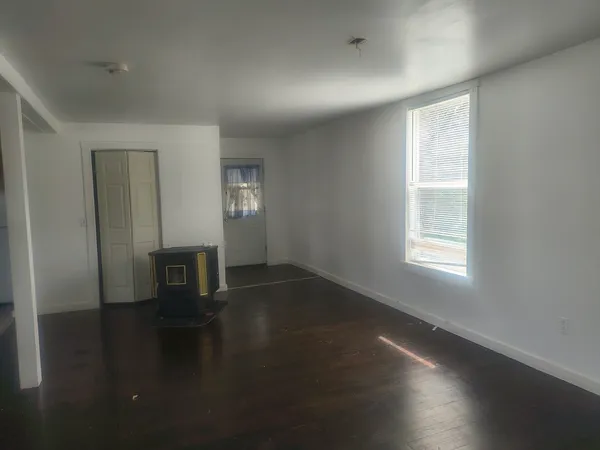 an empty room with wooden floor and windows with curtains