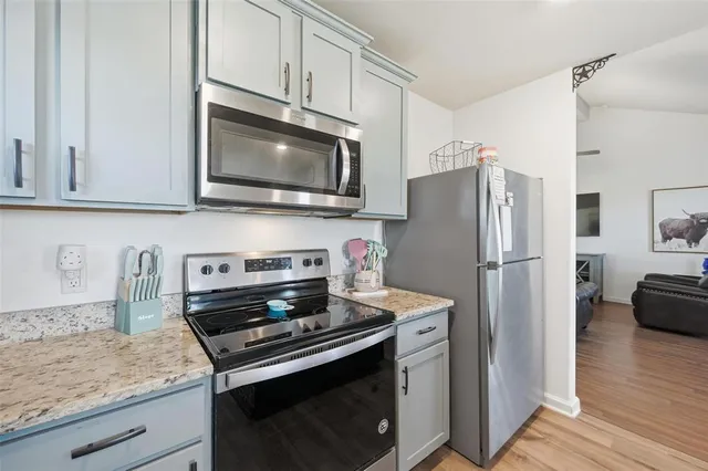 a kitchen with granite countertop a stove microwave and refrigerator
