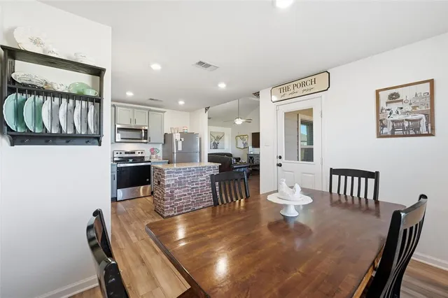 a living room with stainless steel appliances furniture a dining table and kitchen view