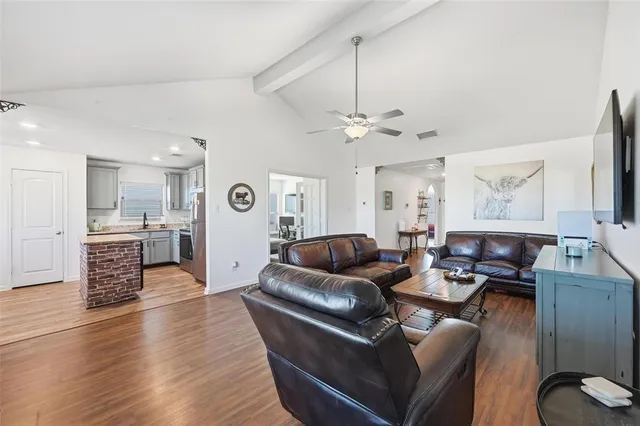 a living room with furniture kitchen view and a wooden floor
