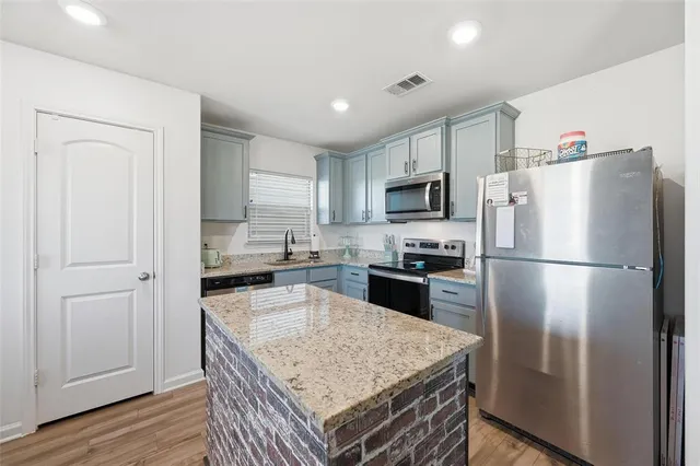 a kitchen with granite countertop a refrigerator a sink a stove a microwave and island