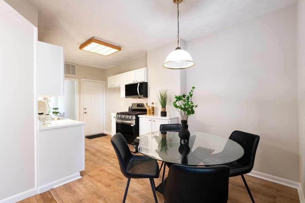 407 Washington Street, Unit 5 Boston, MA 02124 - Photo 7 of 24 a dining room with furniture a chandelier and wooden floor