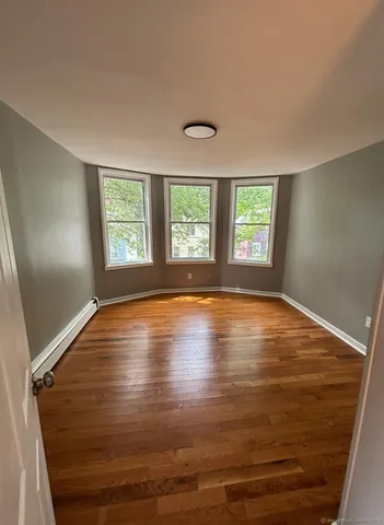 a view of empty room with window and wooden floor