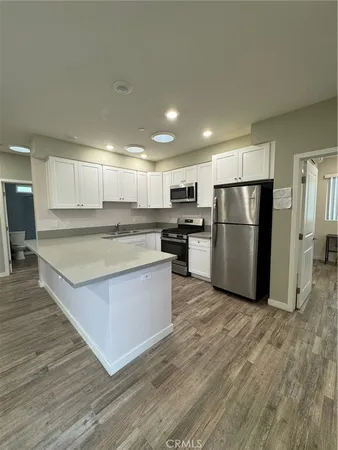 a large kitchen with stainless steel appliances a refrigerator and a stove top oven