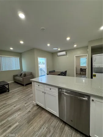 a large kitchen with stainless steel appliances a large counter top a stove and a wooden floors