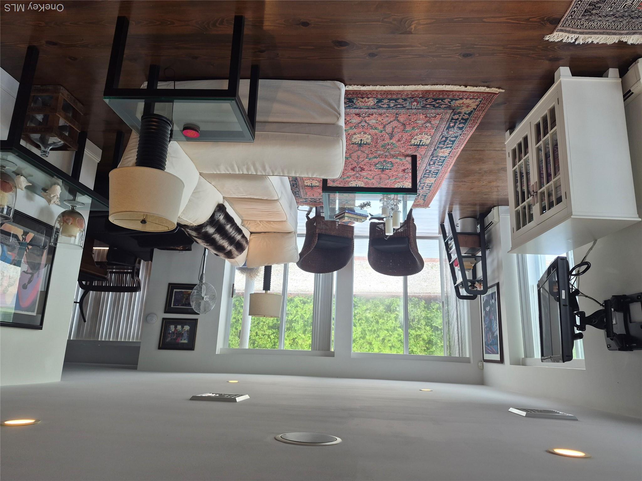2 South Valley Road Hampton Bays, NY 11946 - Photo 5 of 19 a living room with furniture a rug a large window and a flat screen tv