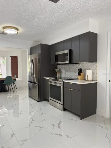 a kitchen with granite countertop a refrigerator and a stove top oven