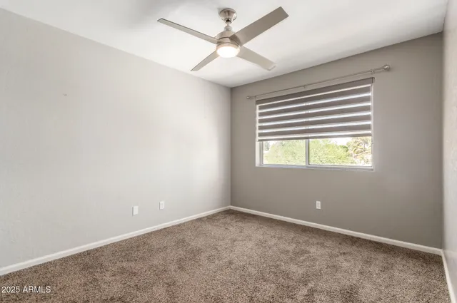 an empty room with windows and fan