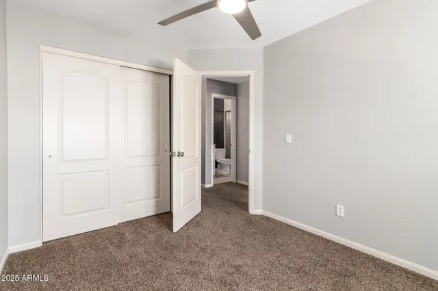 an empty room with closet and a ceiling fan