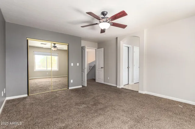 an empty room with ceiling fan and window