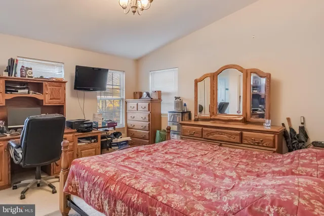 a bedroom with a bed a flat screen tv and chairs