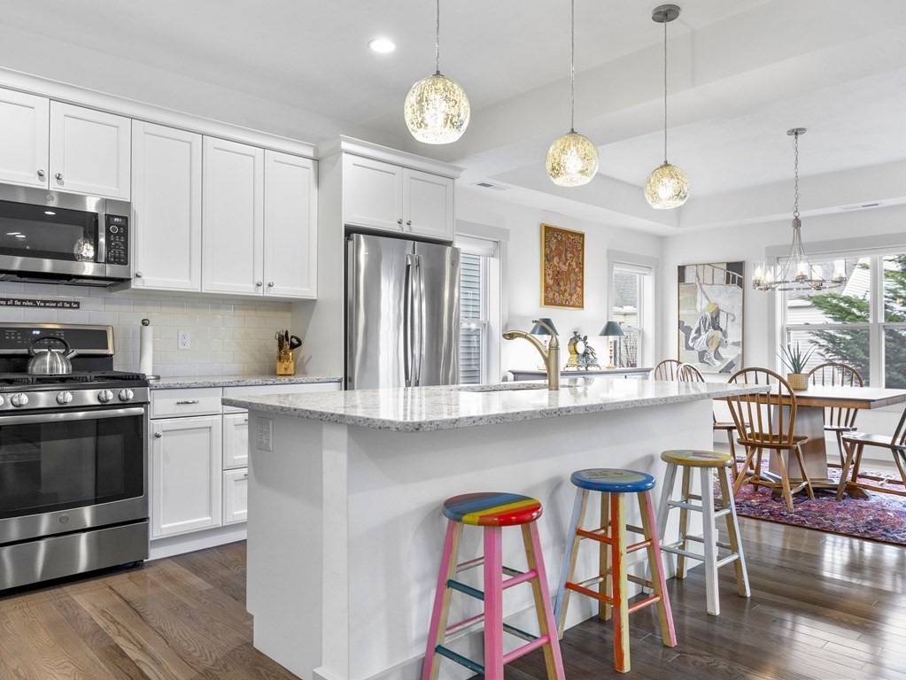 34 Lantern Way, Unit 34 Ashland, MA 01721 - Photo 3 of 30 a kitchen with stainless steel appliances granite countertop a stove a refrigerator a kitchen island a dining table and chairs with wooden floor