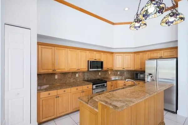 a kitchen with granite countertop a refrigerator a stove a sink a dining table and chairs with wooden floor