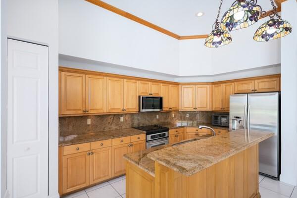 576 Northwest 120th Drive Coral Springs, FL 33071 - Photo 3 of 23 a kitchen with granite countertop a refrigerator a stove a sink a dining table and chairs with wooden floor