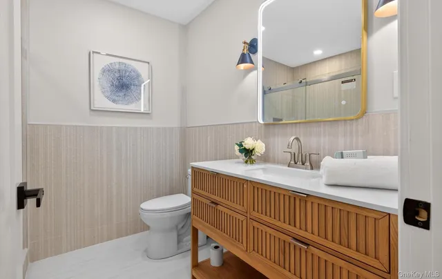 a bathroom with a granite countertop toilet sink and mirror