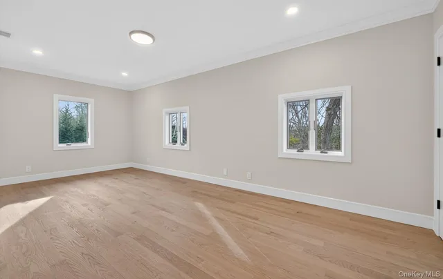 a view of an empty room with window and wooden floor