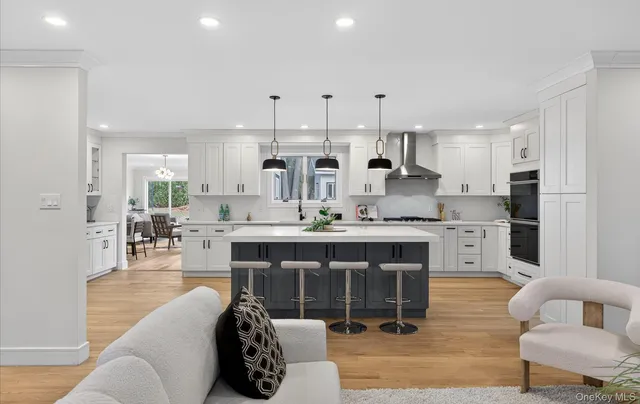 a open kitchen with stainless steel appliances granite countertop a stove a sink dishwasher a refrigerator and white cabinets with wooden floor