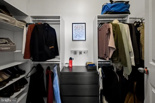 a view of walk in closet with clothes and shoes