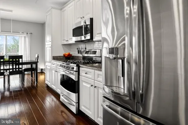 a kitchen with stainless steel appliances a stove a microwave and a view of living room