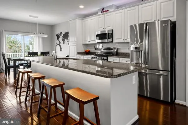 a kitchen with stainless steel appliances granite countertop a refrigerator a stove a sink a dining table and chairs