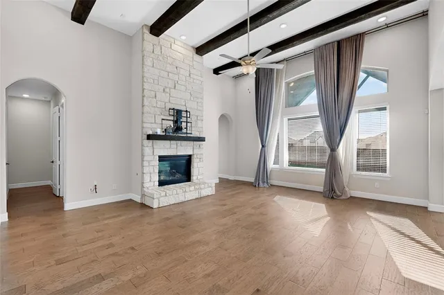 an empty room with wooden floor a fireplace and windows