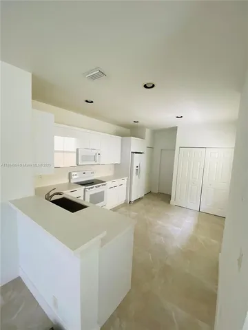 a kitchen with a sink a stove a refrigerator and white cabinets