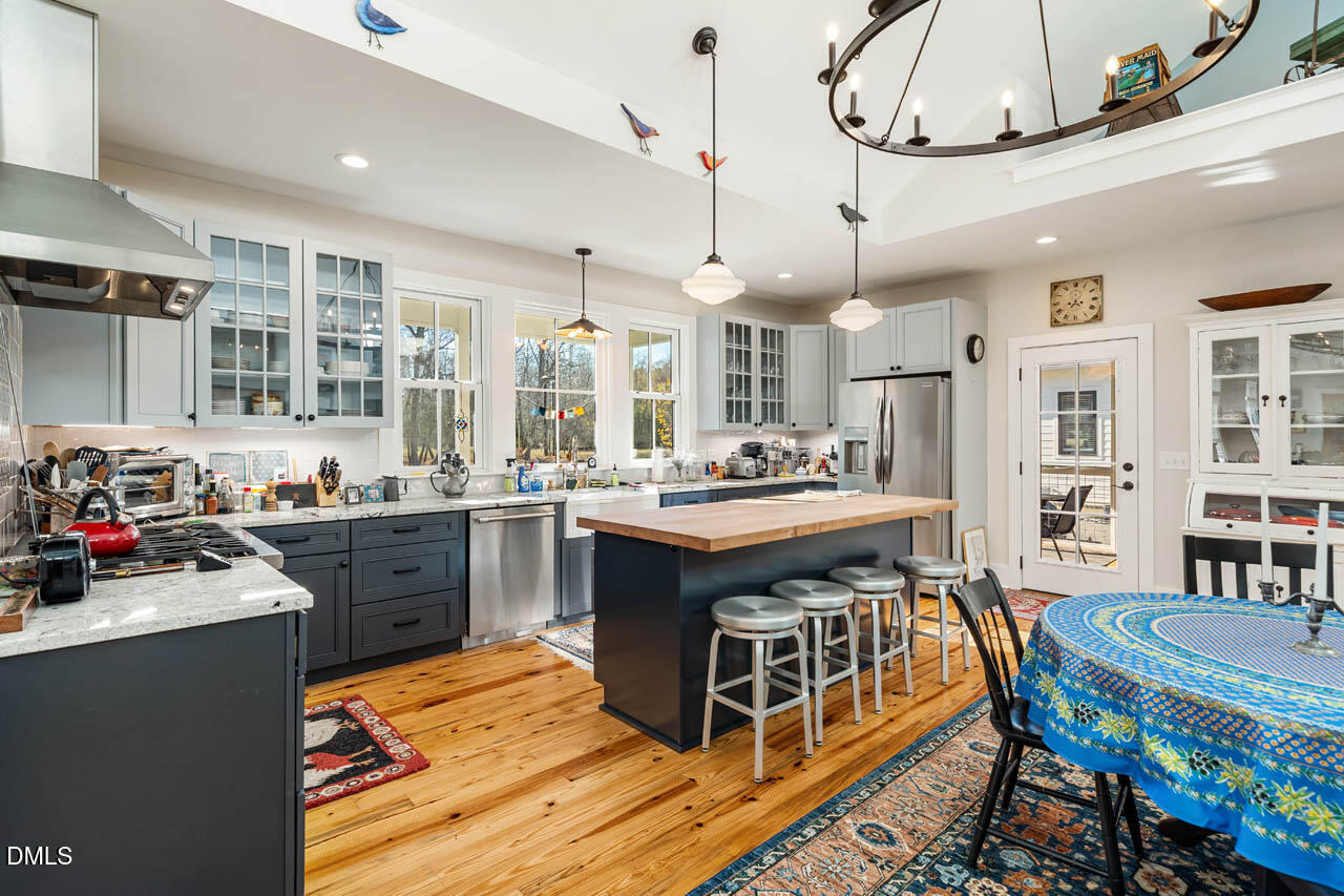 3833 Blakely Way Efland, NC 27243 - Photo 25 of 69 a kitchen with stainless steel appliances granite countertop a stove a sink dishwasher a dining table and chairs with wooden floor