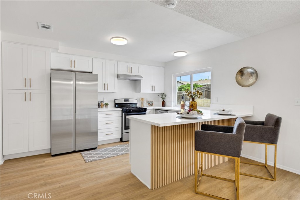 12799 Reed Avenue Grand Terrace, CA 92313 - Photo 1 of 1 a kitchen with a refrigerator a stove top oven a sink dishwasher and a dining table with wooden floor