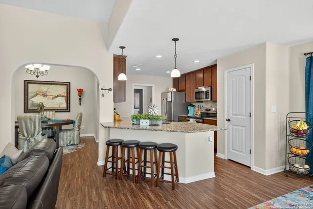 a kitchen with stainless steel appliances granite countertop wooden floors and table