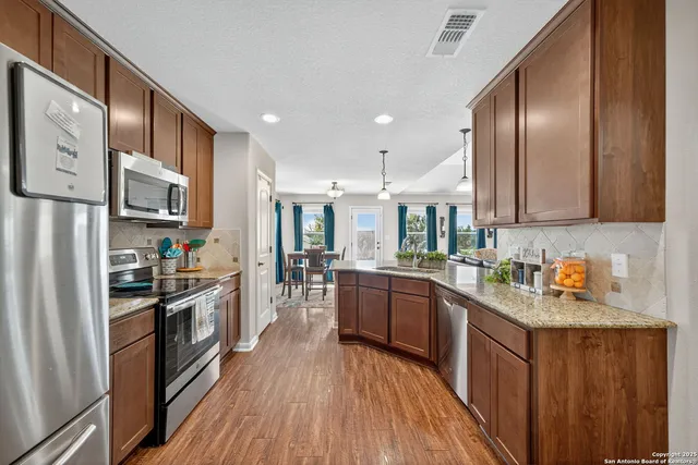 a kitchen with stainless steel appliances granite countertop lots of counter top space a refrigerator a stove top oven and cabinets