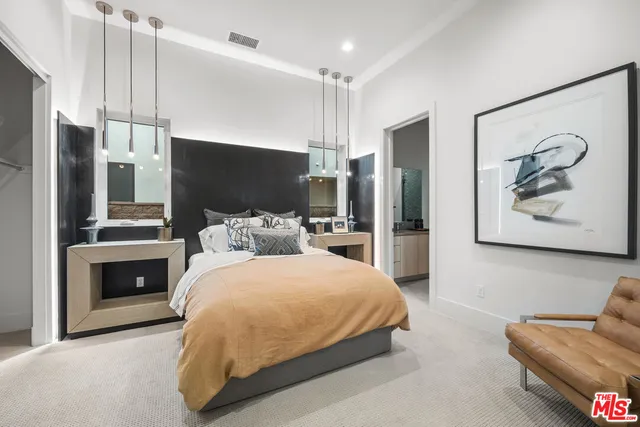a bedroom with a bed couch chandelier and window