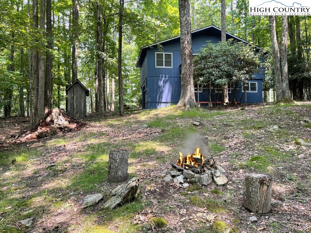 911 Pine Ridge Road Beech Mountain, NC 28604 - Photo 3 of 22 a view of a wooden house with a yard and large trees