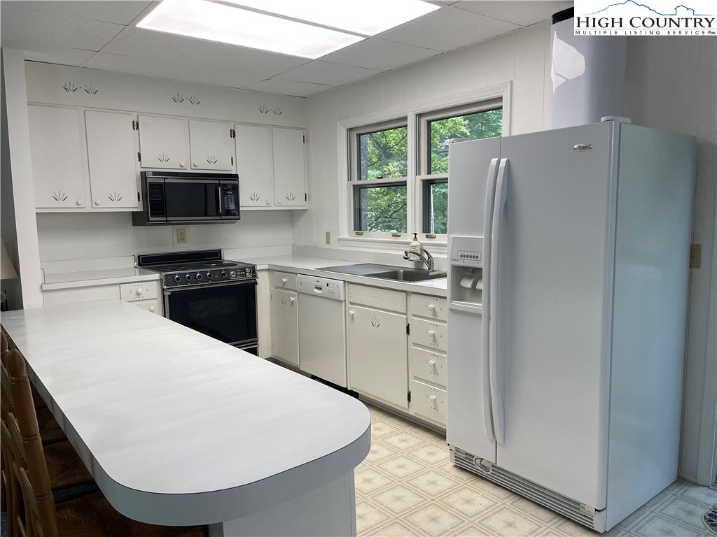 911 Pine Ridge Road Beech Mountain, NC 28604 - Photo 7 of 22 a kitchen with a white stove top oven and refrigerator